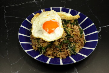 Fried spicy minced pork rice topping with fresh and organic chicken egg yolk serving on the plate. Famous special street food menu in Asia. 