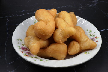 Traditional deep fried dough stick serving on the plate. Chinese cruller or donut, Famous side dish breakfast menu and snack in restaurant. 