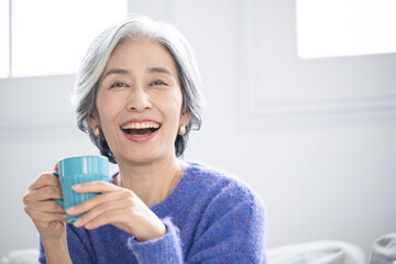 Senior woman with gray hair holding cup with drink Closeup of healthy smile