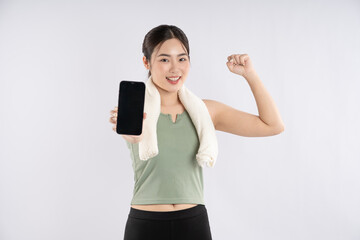 Portrait of young asian girl wearing sports clothes using phone and posing on white background