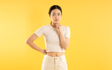 Portrait of young Asian girl posing on yellow background