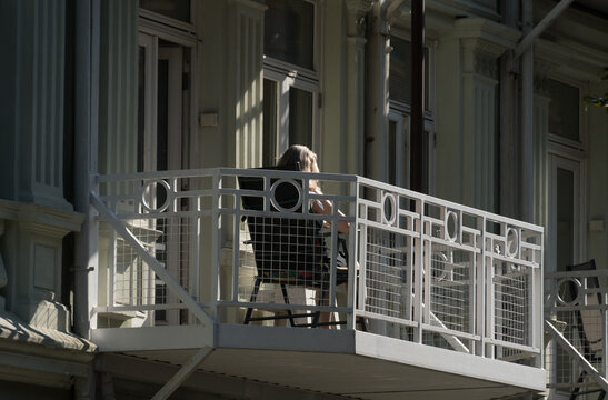 Elderly woman enjoys sun  on her balcony