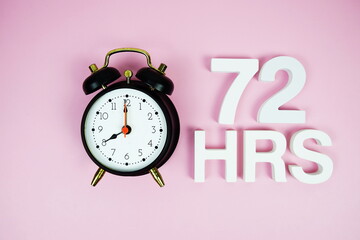 72 Hrs alphabet letters and alarm clock top view on pink background
