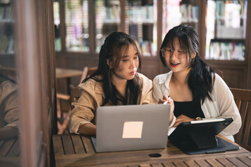 Two women sitting at a table looking at a laptop