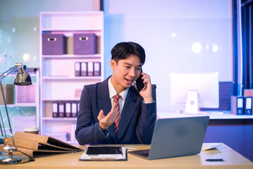 Businessman drinking coffee to get some energy for working overtime sitting at desk using computer and doing overtime