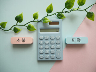 電卓と本業、副業の文字　比較　収入