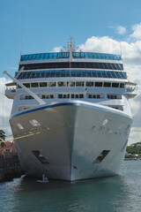Luxury classic cruiseship cruise ship liner Nautica docked at pier terminal in Hamilton, Bermuda on sunny day with port infrastructure and city skyline
