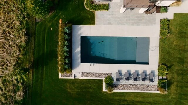 a stop down aerial drone shot of a luxury backyard pool outside of a home