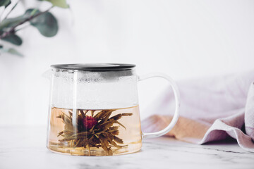 Glass tea pot with Flower Chinese tea on light background. © Nelli Kovalchuk