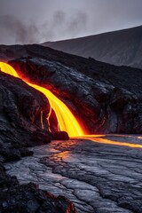 Fototapeta premium Molten lava flowing through dark volcanic rock.