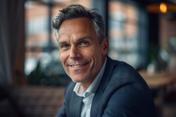 Obraz premium High-resolution portrait of a handsome, smiling CEO in formal business attire exhibiting confidence and leadership qualities in a corporate setting