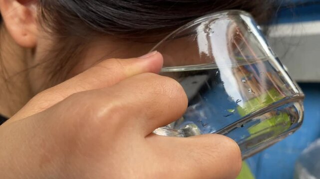 Close up asian woman wash eye irritation in glass of clean water. Cleaning eye concept 