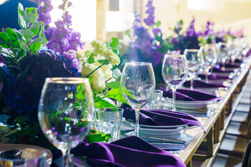 Beautiful festive table setting with flowers and purple napkins. 