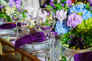 Beautiful festive table setting with flowers and purple napkins. 