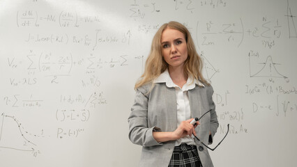 Fototapeta premium A Caucasian woman stands at a blackboard with written formulas.