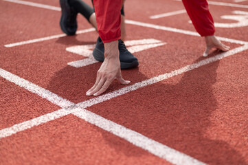 Fototapeta premium Cool Asian guy wearing red exercise clothes. Starting out on the running lane in the stadium. Both hands are placed on the floor close to the body. outdoor exercise maintaining health active living