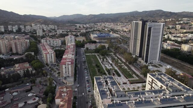 The urban area shows tall buildings surrounded by mountains from an aerial perspective
