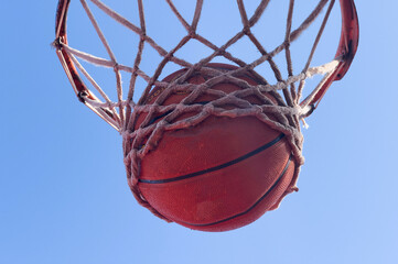 Basketball scoring a basket as it goes through the hoop and making a swish in the net