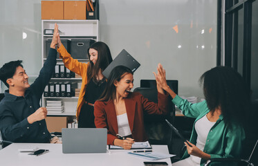 Obraz premium Young corporate employees sitting in office looking at laptop screen reading good news excited happy team diverse people celebrating victory win command success excellent result professional teamwork