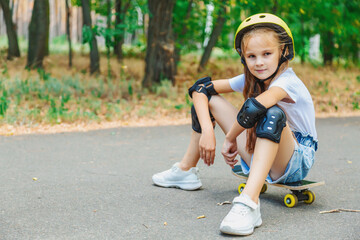 little smiling girl wearing helmet, elbow and knee support for body safety protect sitting on a skateboard