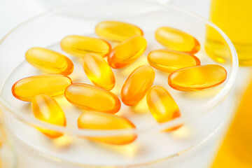 Petri dish with fish oil capsules inside, vitamin D, omega softgels, supplements, keto diet.