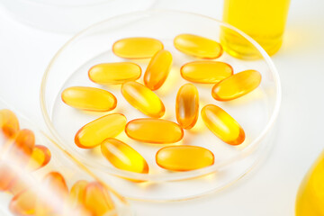 Petri dish with fish oil capsules inside, vitamin D, omega softgels, supplements, keto diet.
