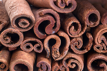 Close-up of rolled cinnamon sticks stacked together, showing natural texture and detail, ideal for food and spice themes.