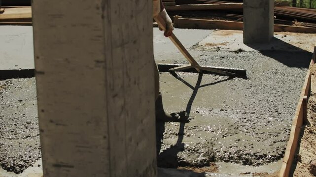 Builder leveling liquid concrete at the construction site