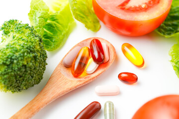 Pills and capsules in wooden spoon with fresh vegetables, Multivitamins and supplement