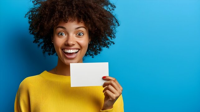Ecstatic young woman holding up a blank card and smiling broadly brimming with excitement and joy as she showcases her gift voucher with a cheerful enthusiastic expression
