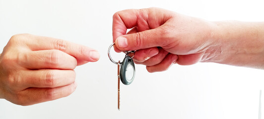 Young adult woman hand holding two metal door keys on light blue table background. Pastel color....
