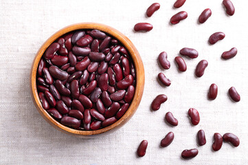 Dried kidney beans in a wooden bowl on linen fabric. Raw, uncooked common kidney beans, a variety of the common bean Phaseolus vulgaris, a vegetarian staple food, and commonly used in chili con carne.