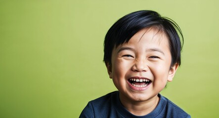 Child Asian boy with strong jawline and straight black hair laughing dark green background