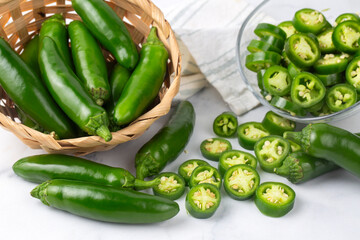 Sliced jalapeno pepper in wooden bowl isolated on white background. Green chili pepper with full depth of field.