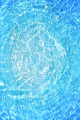 Blue water with ripples on the surface. Defocus blurred transparent blue colored clear calm water surface texture with splashes and bubbles. Water waves with shining pattern texture background.