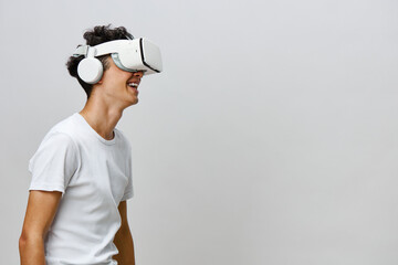 Virtual reality experience, young man wearing VR headset, smiling, engaging with technology, light gray background, modern atmosphere, innovation and entertainment concept