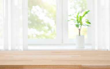 Wood table top on blur curtained window and abstract green garden in sunlight background