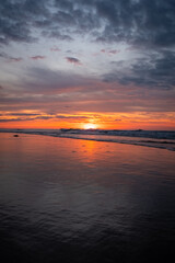 Obraz premium The serene beach at sunset exudes tranquility, sky reflecting in calm ocean water, creating a peaceful atmosphere