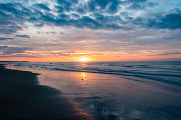 Experience a serene beach sunset with vibrant colors and calm waves, ideal for a tranquil evening by the sea