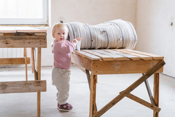 A little girl stands in an empty house where construction work