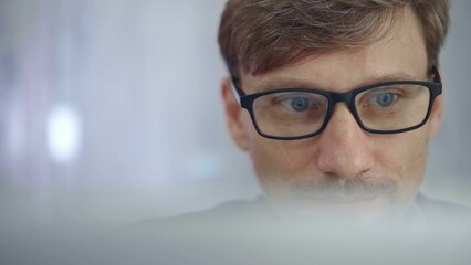 Fototapeta premium Businessman with glasses looking intently obscured partially by a translucent surface of laptop. Business people concept