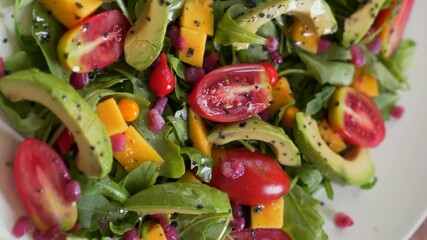 Tropical salad with arugula, avocado, mango, cherry tomatoes and pomegranate seeds. Close up. Vertical video. - Powered by Adobe