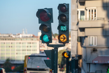 Traffic signals indicating bus lane and pedestrian crossing in an urban area during daylight