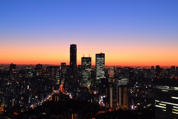 Fototapeta premium A breathtaking sunset paints the skyline over a bustling cityscape with twinkling lights