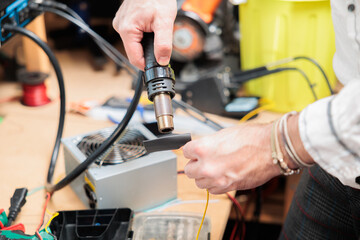 dettagli in primo piano delle mani di un giovane uomo caucasico mentre lavora alla riparazione di un apparecchio elettronico