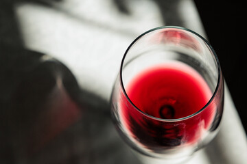 vista macro di un calice visto da sopra, riempito con del vino rosso ed appoggiato su un tavolo,...