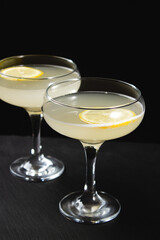 Yellow cocktail with lemon wedge on black background