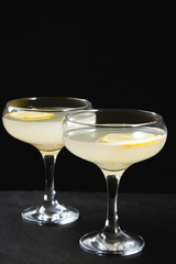 Yellow cocktail with lemon wedge on black background