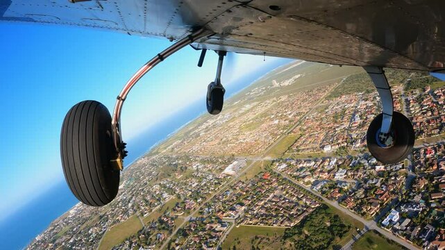 Light three wheels training airplane doing exercises in the air. Performance steep turns with bank angle of 45 degrees. Fly overhead private residential territory. View from the bottom of aircraft.