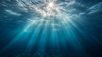 The deep blue ocean surface is visible from beneath the waves. Sunlight streams down, creating a beautiful underwater scene.  The seafloor is dimly lit in the distance.